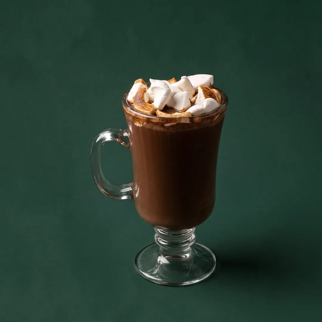 Hot chocolate crowned with toasted marshmallows in a glass mug