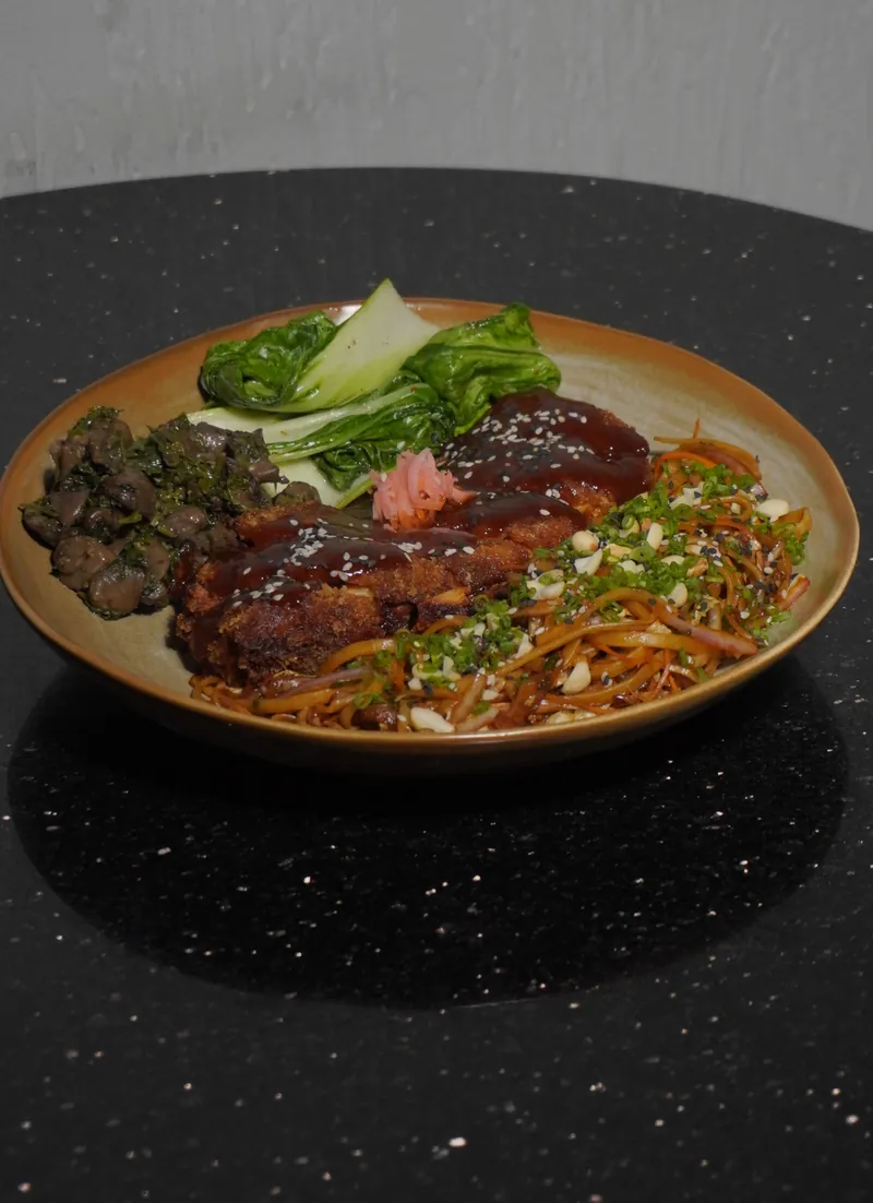 Chicken katsu yakisoba with pak choi and sliced greens